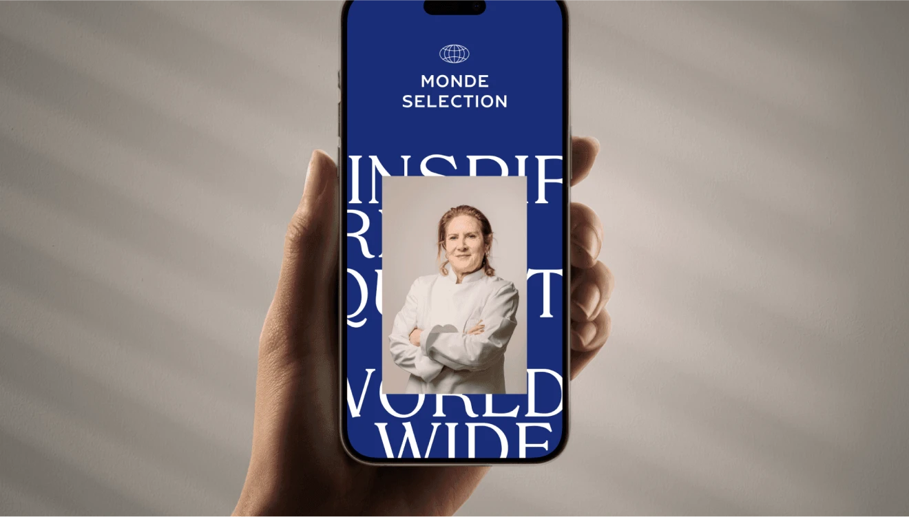 Mockup visualization of an iPhone held in hand, displaying the website for the Monde Selection Rebranding Project. Design by Nemesis Studio and Fabio Besti
