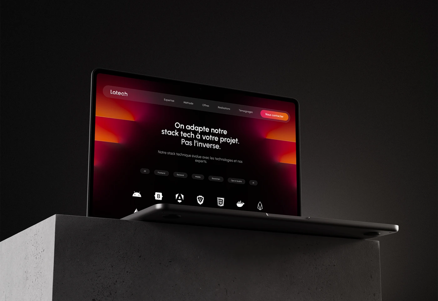 Dark ambient mockup of an MacBook Pro on a concrete base displaying the desktop version of the Latech web design, on the tech stack section, reading 