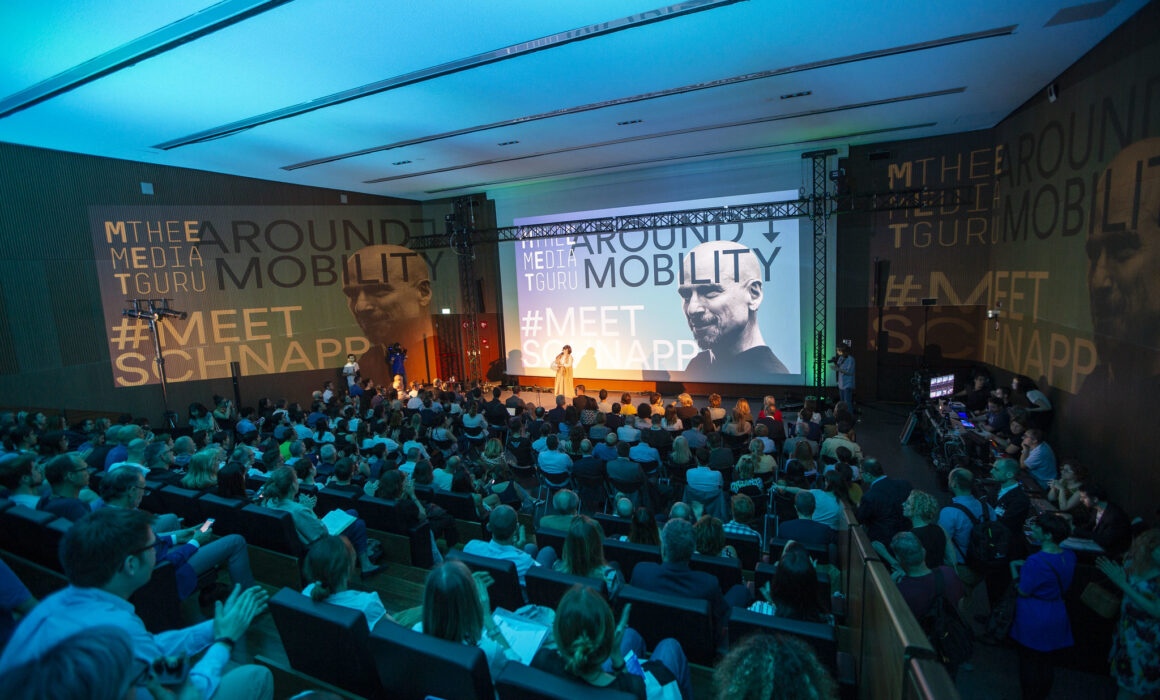 Panoramic view of the stage and audience during the opening speech of Maria Grazia Mattei at the Meet the Media Guru | Around Mobility Event with Jeffrey Schnapp at Mudec Milano co-created by MEET, Fondazione Bassetti & Fabio Besti. Big screen showing the slide on Movability, a new concept developed by Schnapp and Piaggio Fast Forward
